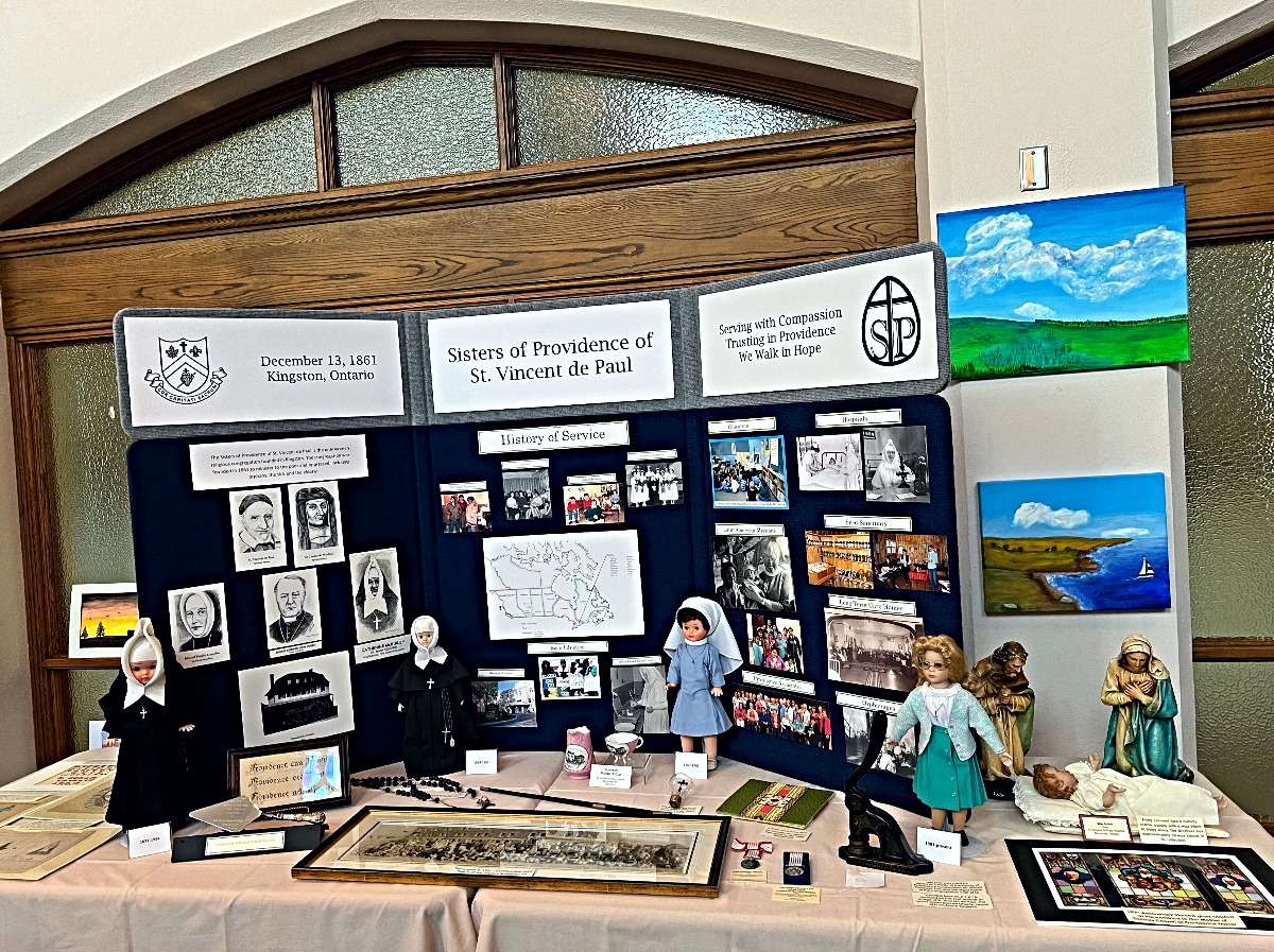 A table with a poster board on top displaying old pictures of Sisters with various memorabilia in front