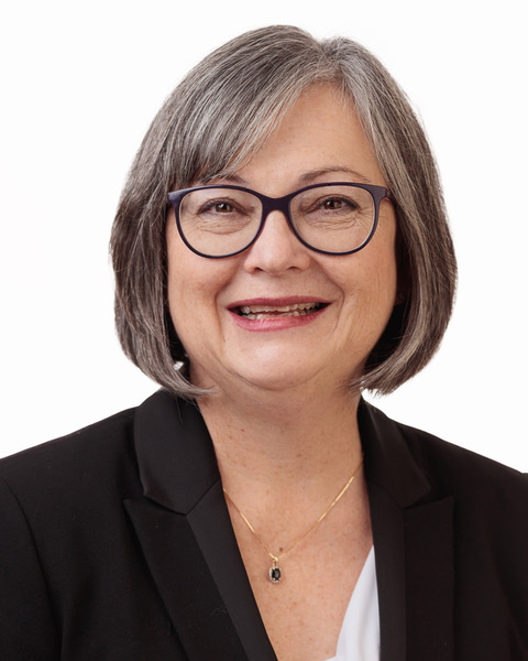 A headshot of a woman wearing glasses and a black blazer.