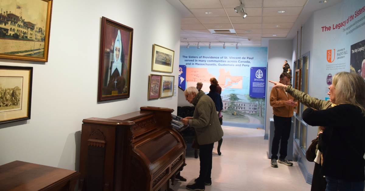 Visitors explore an exhibit about the history and ministries of the Sisters of Providence of St. Vincent de Paul, with illuminated displays.