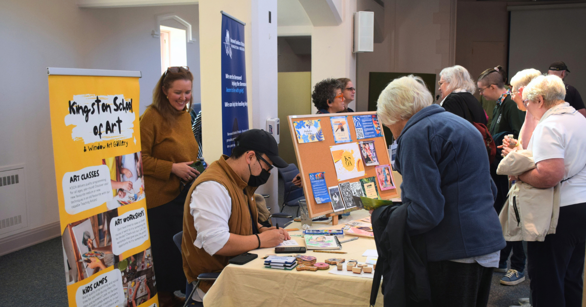 Visitors stop at the Kingston School of Art information table during the Community Open House, where artwork, program materials and a colourful banner promoting art classes, workshops and kids’ camps are on display.